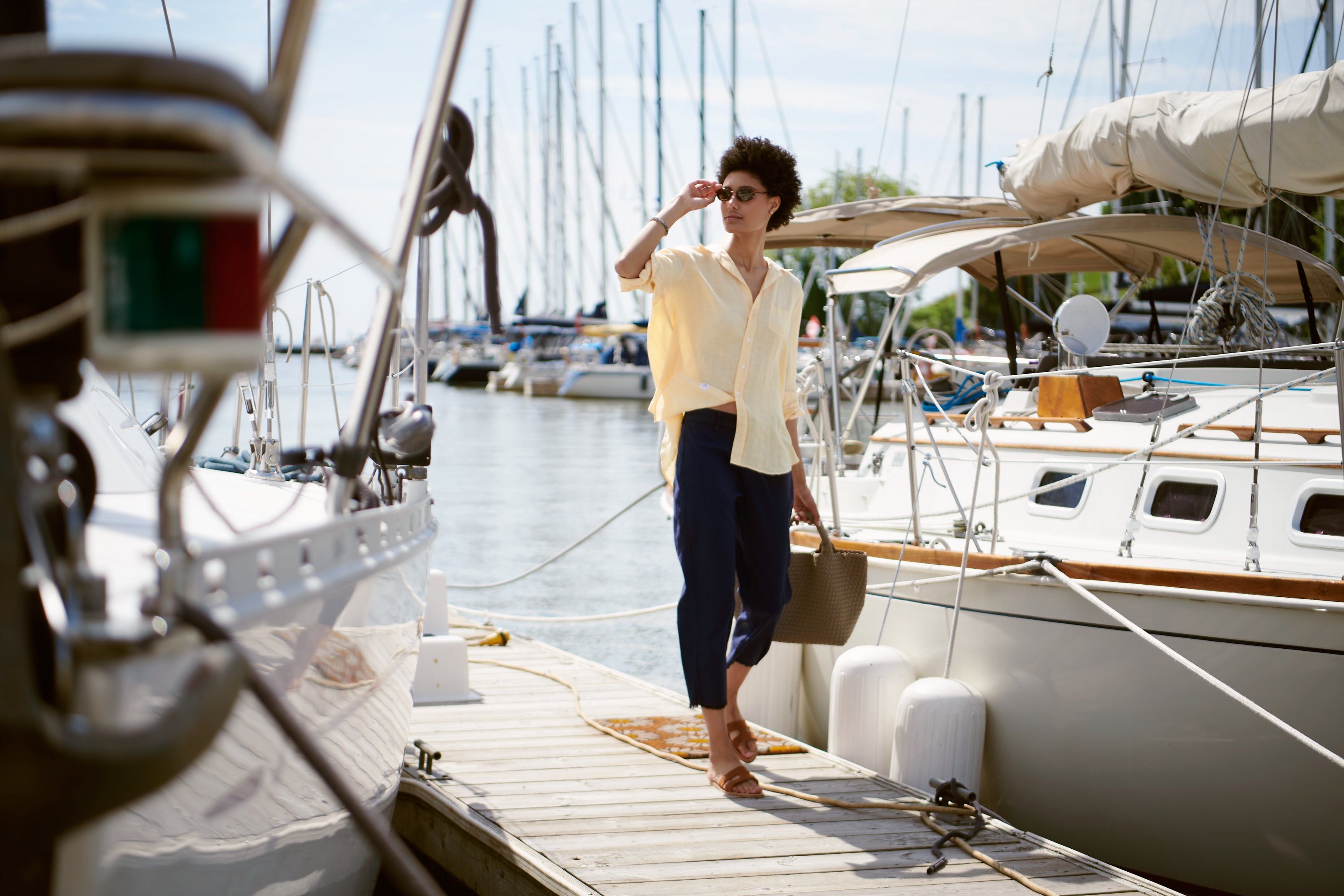 Woman stands on a dock beside a yacht wearing Frank & Eileen's relaxed button up shirt and linen pant