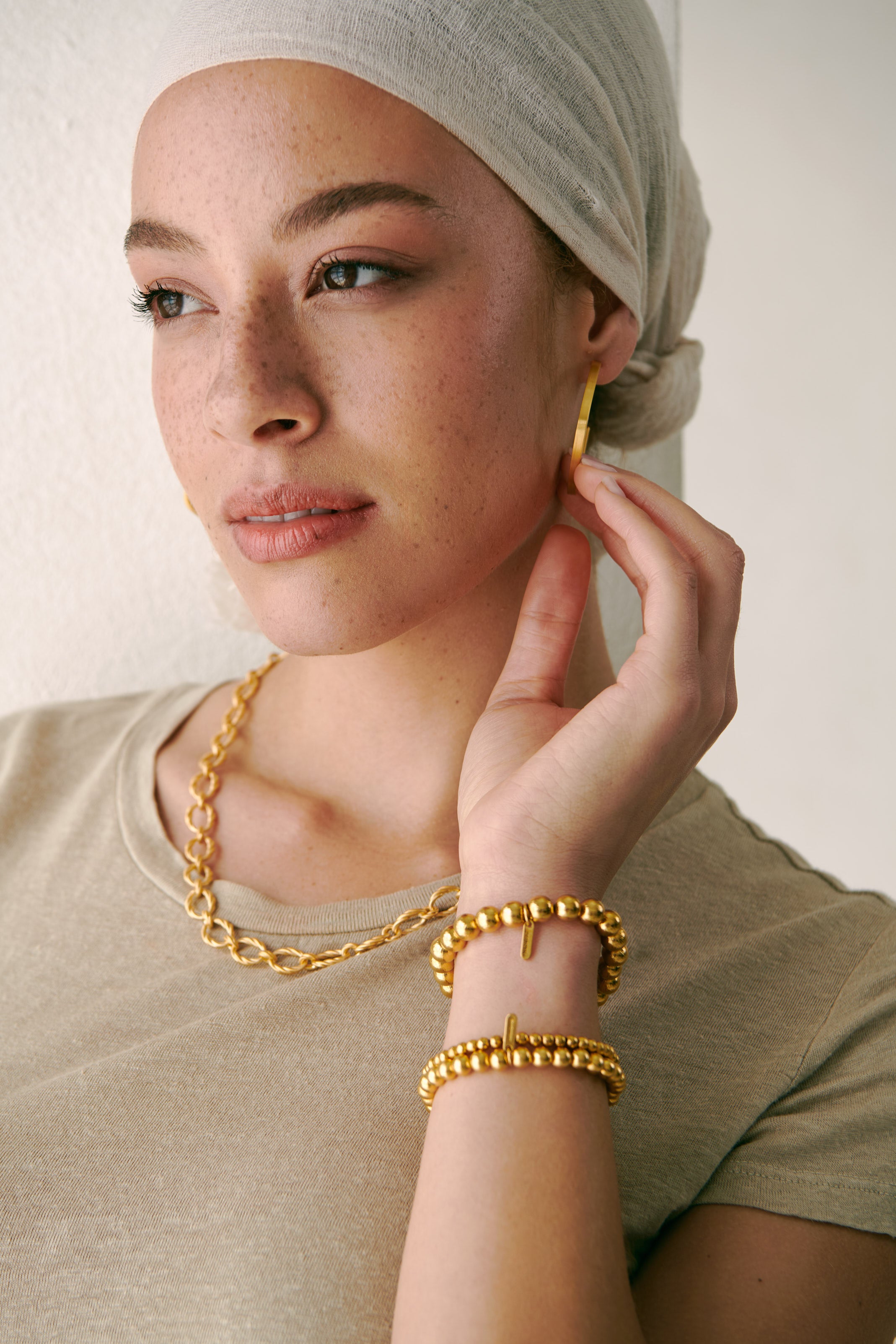 Casey Linen Knit Crewneck Top by Velvet, styled with gold jewelry; Midi Square Hoops, a Zen Beaded Stretch Bracelet set, and Signature Collar Necklace by Dean Davidson